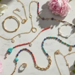 Bijoux tendenze primavera estate: collezione di anelli geometrici dorati, bracciali colorati e collane minimaliste in stile contemporaneo