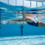 Esercizi nuoto tonificare: atleta che esegue lo stile libero in piscina mostrando spalle forti e braccia toniche