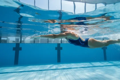 Esercizi nuoto tonificare: atleta che esegue lo stile libero in piscina mostrando spalle forti e braccia toniche